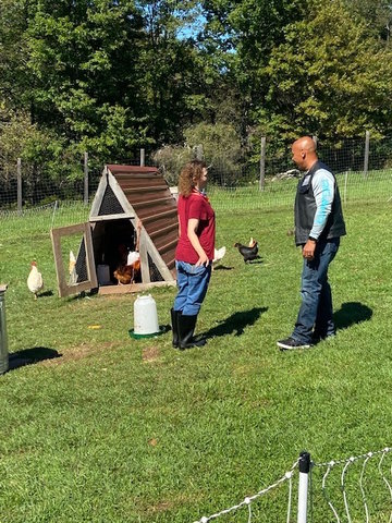 Tara, who works on the farm, introduces Knights Order member and New Hope Community parent David Lee to the many chickens who supply fresh eggs.